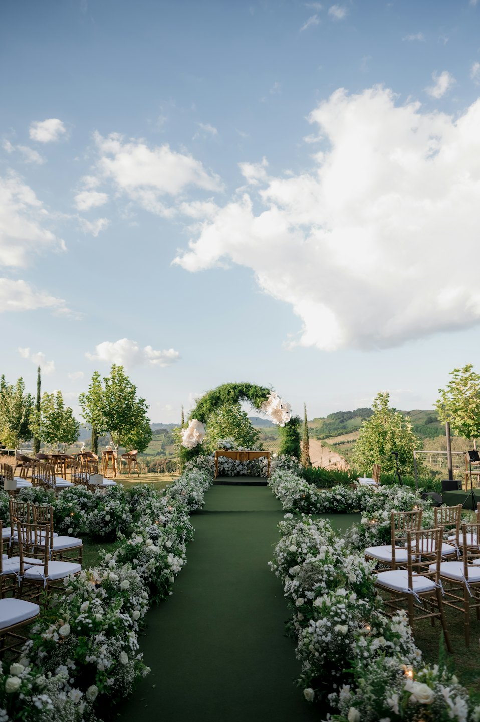 Outdoor wedding archway and aisle decorated with flowers in a vineyard.