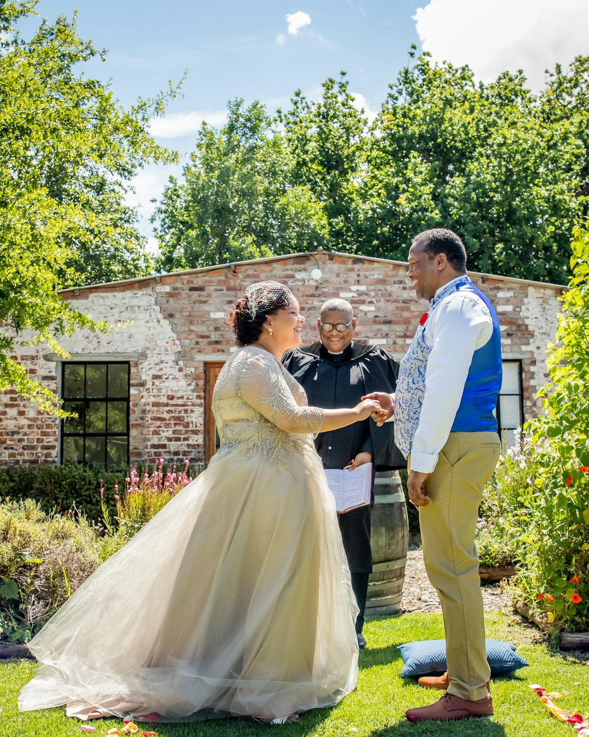 A couple holds hands while exchanging wedding vows in a garden.