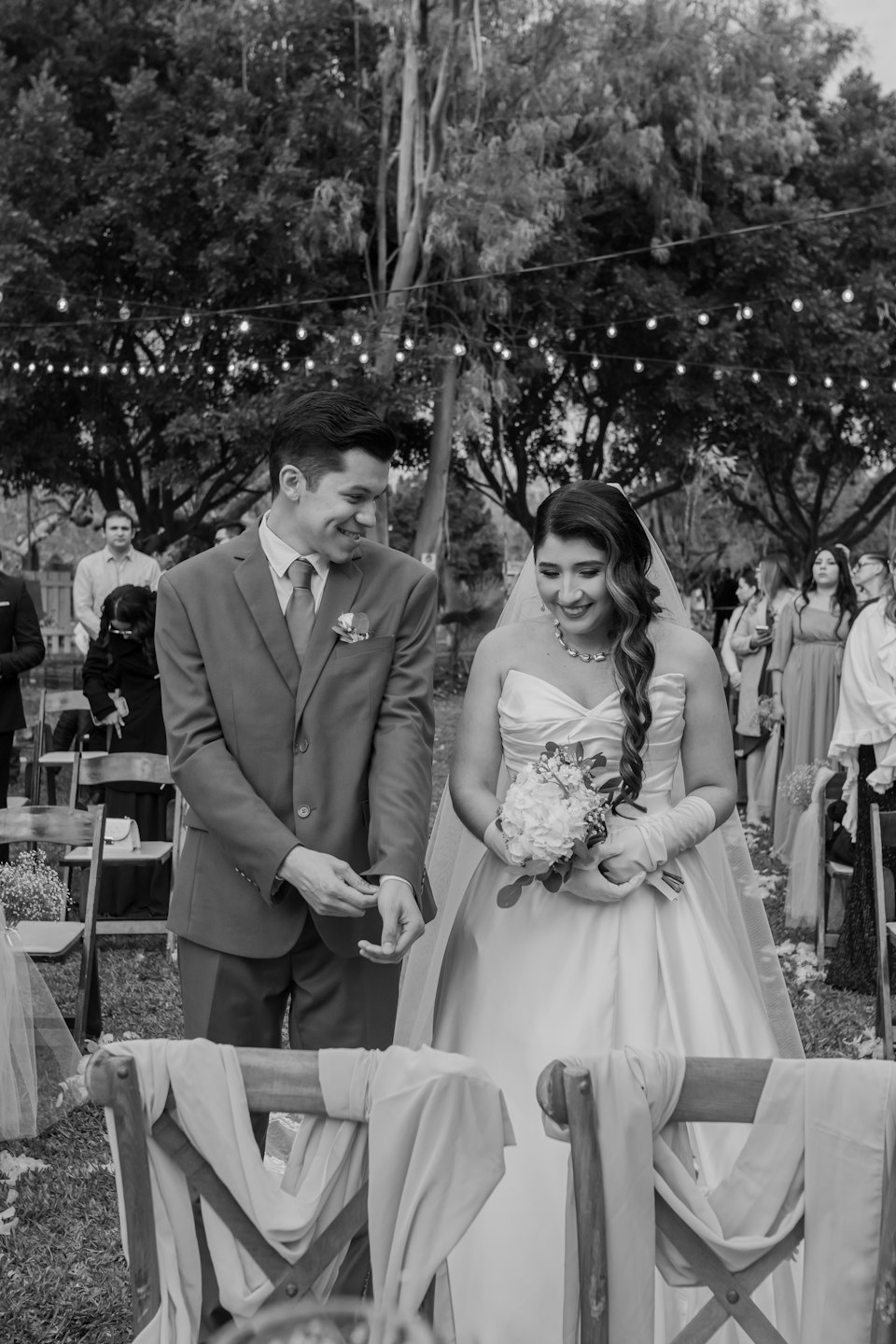A bride and groom smile at each other during their wedding ceremony.
