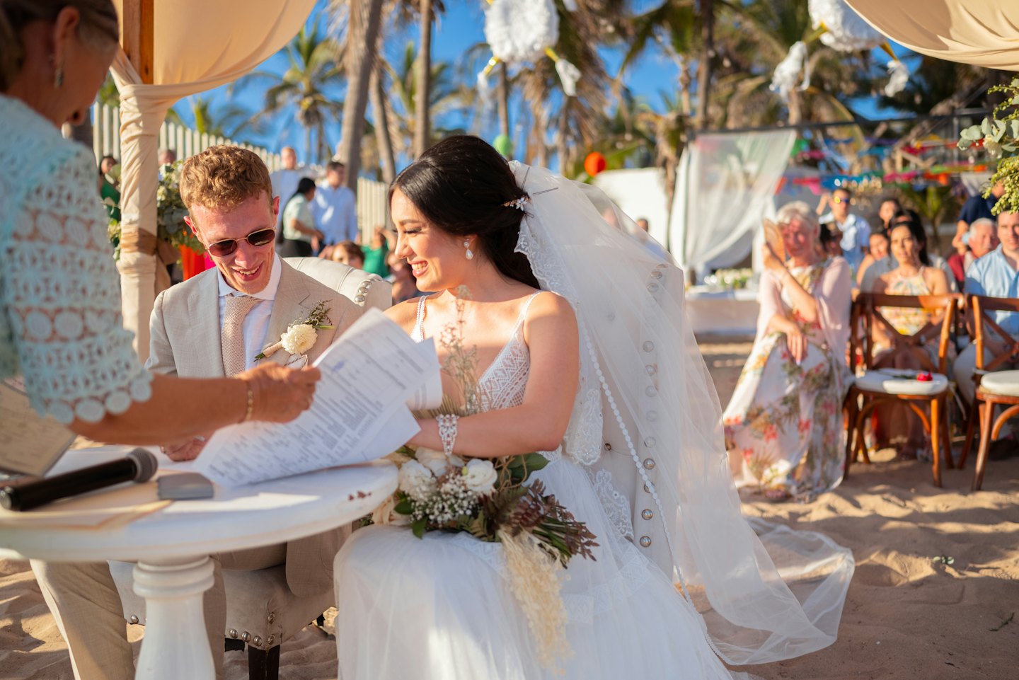 An officiant watches as the bride and groom sign documents.
