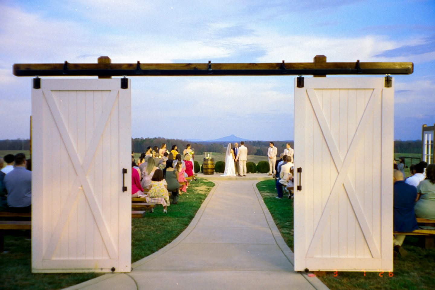 A bride and groom exchange wedding vows outdoors before guests.